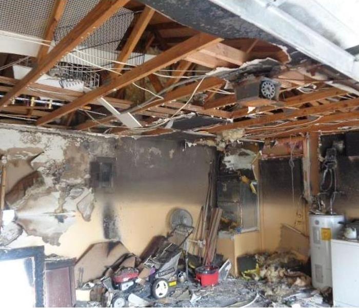 Garage with a lawnmower and washer-dryer units surrounded by fire and smoke damage